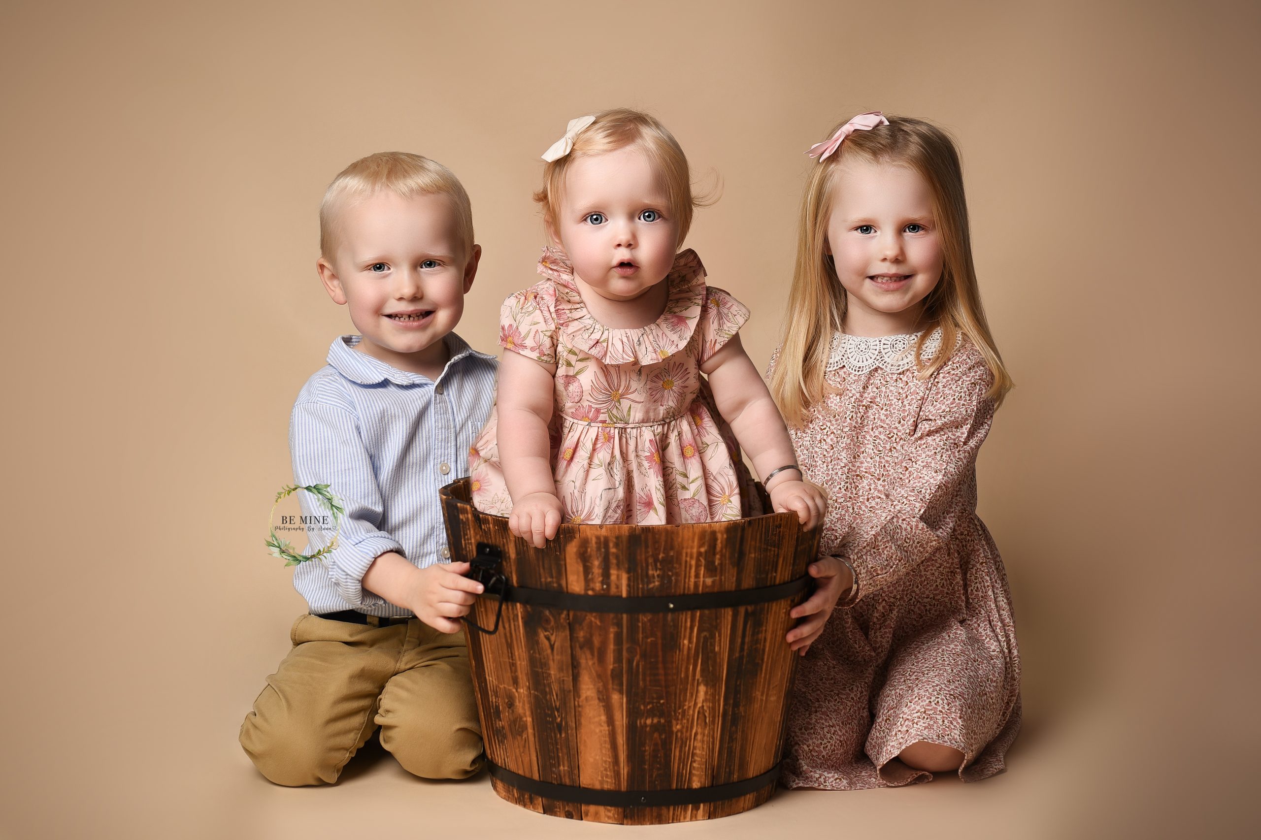 young siblings with toddler in water bucket